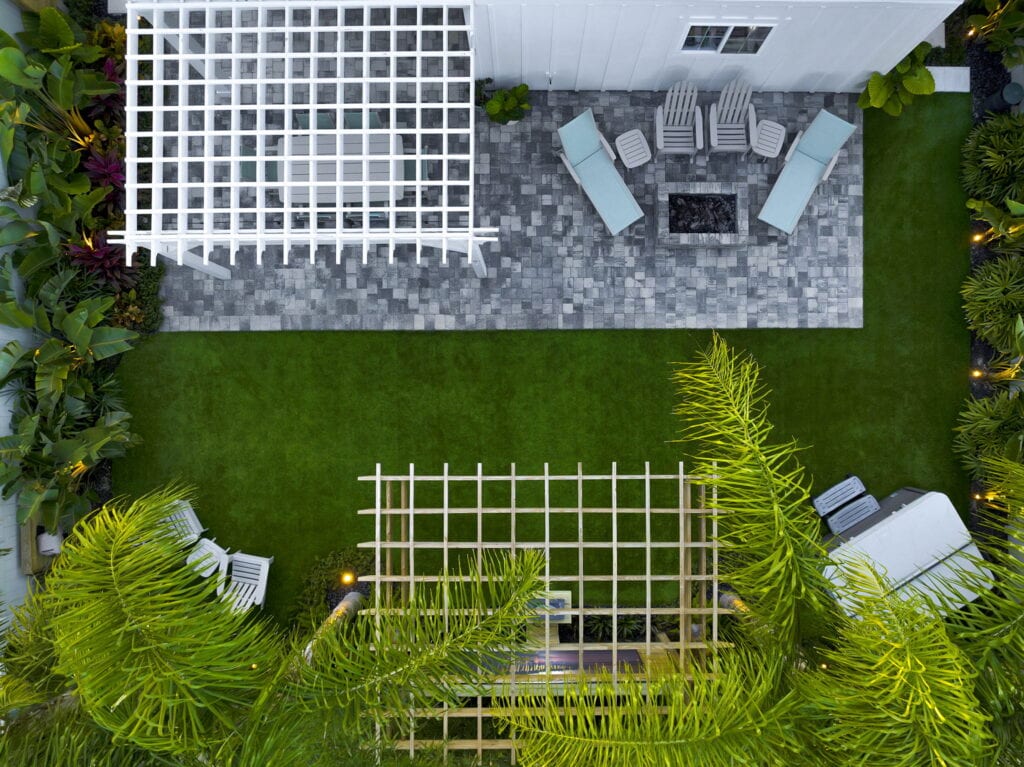Aerial view of a landscaped backyard with lawn, patio, and outdoor seating area.